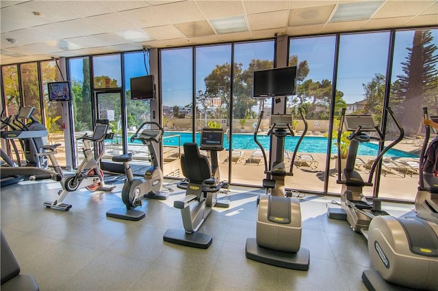 workout area with a wall of windows and a drop ceiling