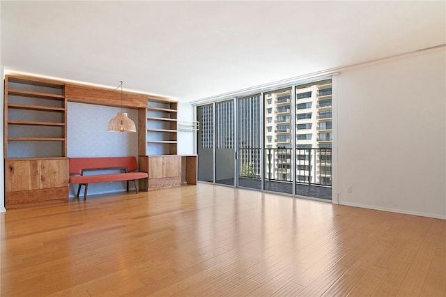 spare room with expansive windows, wood finished floors, and built in features