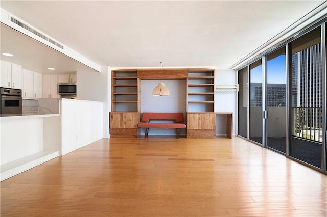 unfurnished living room featuring light wood-style flooring and built in features