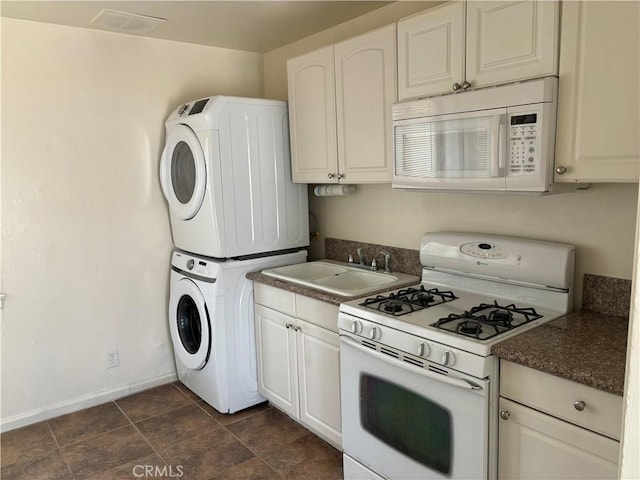 6688 Yucca Ave Unit 29, Palms, CA 92277 - kitchen featuring white appliances, stacked washer / dryer, dark countertops, baseboards, and a sink