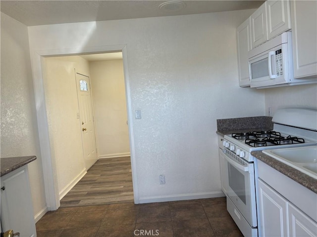 6688 Yucca Ave Unit 29, Palms, CA 92277 - kitchen featuring white appliances, white cabinets, baseboards, and dark tile patterned flooring
