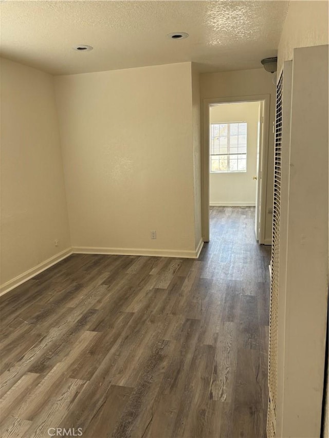 6688 Yucca Ave Unit 29, Palms, CA 92277 - unfurnished room featuring a textured ceiling, dark wood-style floors, baseboards, and a heating unit