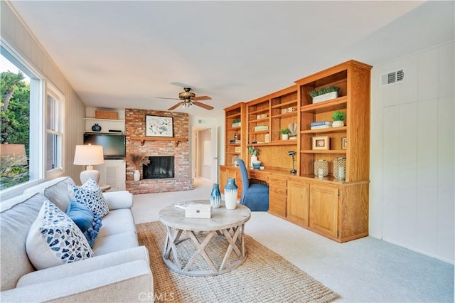 living area featuring ceiling fan, light carpet, and a brick fireplace