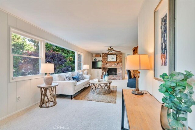 living room with a fireplace, a ceiling fan, and carpet