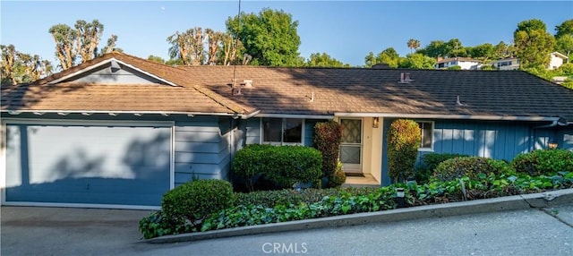 view of front of house with an attached garage and roof with shingles