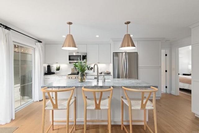kitchen featuring stainless steel appliances, light wood finished floors, a breakfast bar, white cabinetry, and recessed lighting