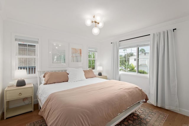 bedroom featuring wood finished floors, crown molding, and baseboards