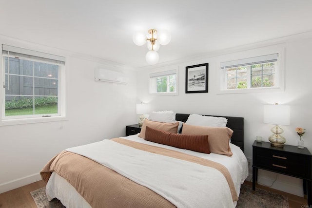 bedroom featuring a wall unit AC, wood finished floors, and baseboards