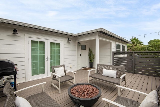 wooden terrace with french doors, area for grilling, and a fire pit