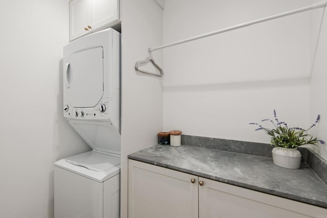laundry room with stacked washer / drying machine and cabinet space