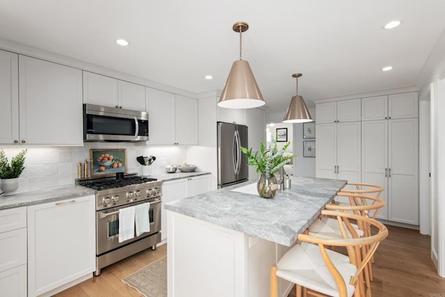 kitchen featuring appliances with stainless steel finishes, a center island, decorative backsplash, light wood finished floors, and recessed lighting