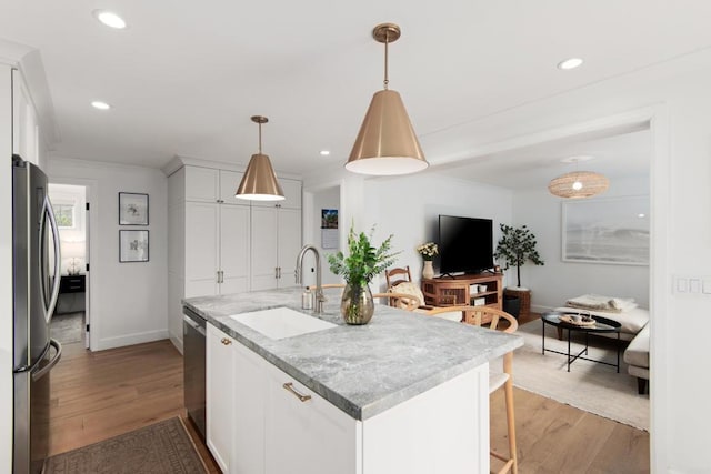 kitchen with a sink, stainless steel appliances, baseboards, light wood-style flooring, and crown molding