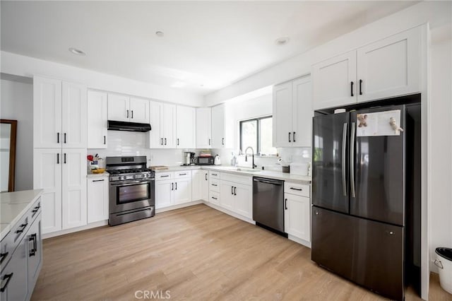 kitchen with freestanding refrigerator, stainless steel gas range, dishwasher, a sink, and under cabinet range hood