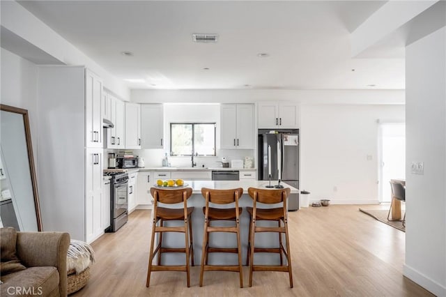 kitchen with appliances with stainless steel finishes, a sink, light wood-style floors, and white cabinets