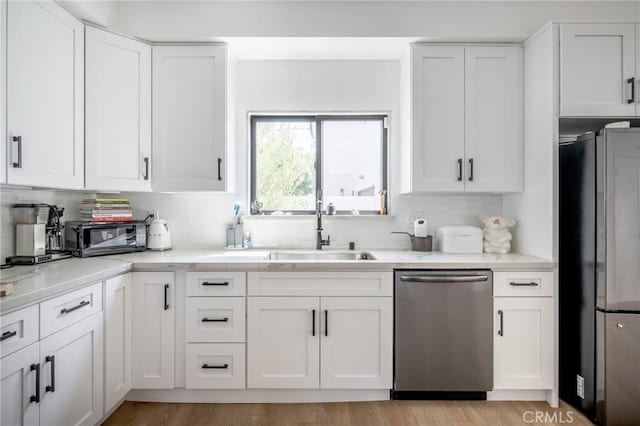kitchen featuring dishwasher, freestanding refrigerator, a sink, and decorative backsplash