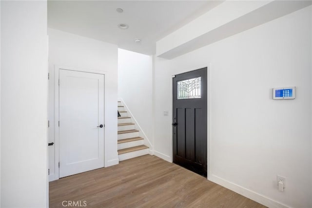 entryway with wood finished floors, stairs, and baseboards