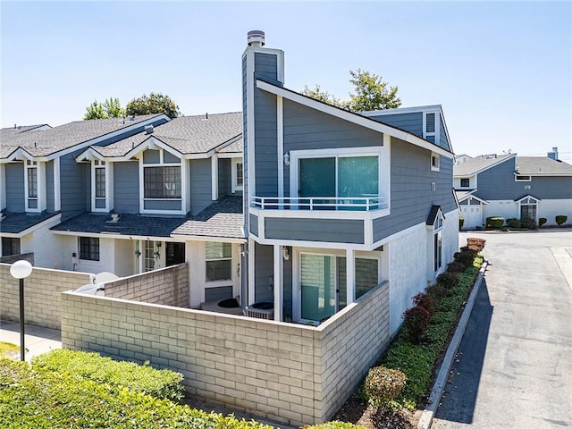 173 N Magnolia Ave Unit A, Anaheim, CA 92801 - view of front of home with a balcony, fence, a chimney, and roof with shingles