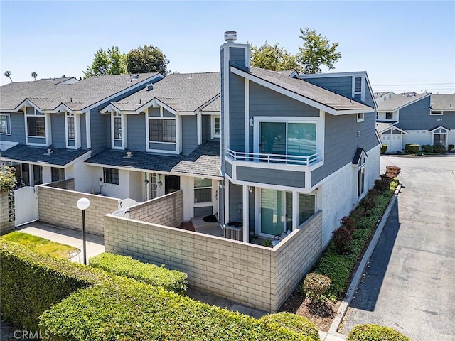 173 N Magnolia Ave Unit A, Anaheim, CA 92801 - view of front of house with a balcony, a chimney, a residential view, roof with shingles, and central AC unit