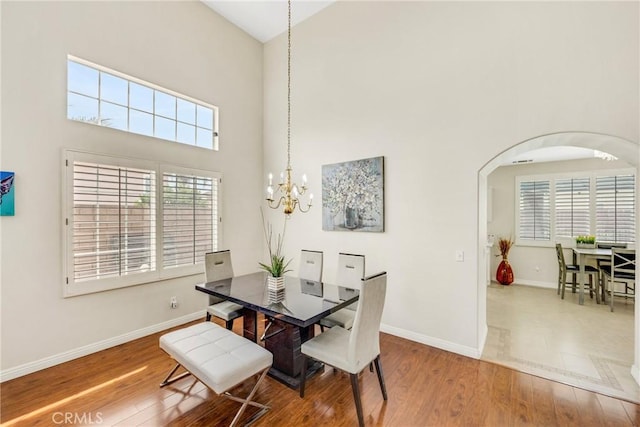 870 E Bermuda Dunes Ct, Ontario, CA 91761 - dining space featuring high vaulted ceiling, baseboards, arched walkways, wood finished floors, and a chandelier