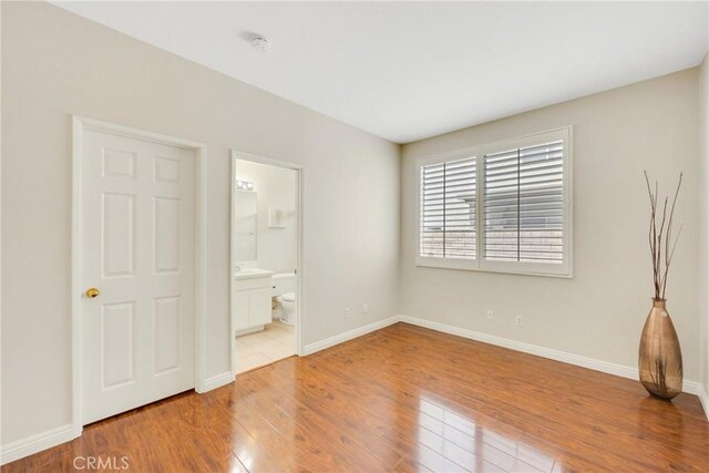 870 E Bermuda Dunes Ct, Ontario, CA 91761 - unfurnished bedroom featuring wood-type flooring, baseboards, and connected bathroom