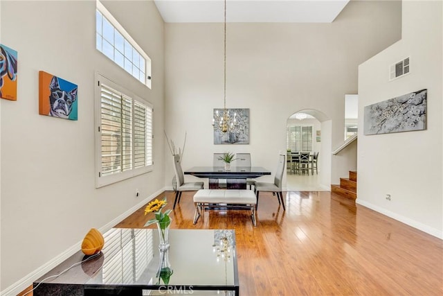 870 E Bermuda Dunes Ct, Ontario, CA 91761 - dining room with a towering ceiling, arched walkways, wood finished floors, a chandelier, and baseboards