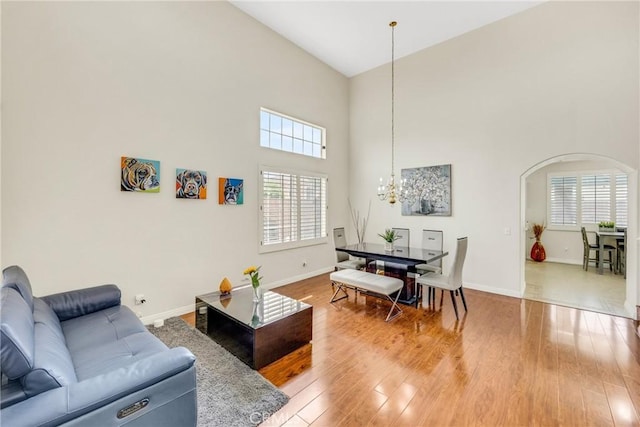 870 E Bermuda Dunes Ct, Ontario, CA 91761 - living room with a chandelier, a high ceiling, baseboards, light wood-type flooring, and arched walkways