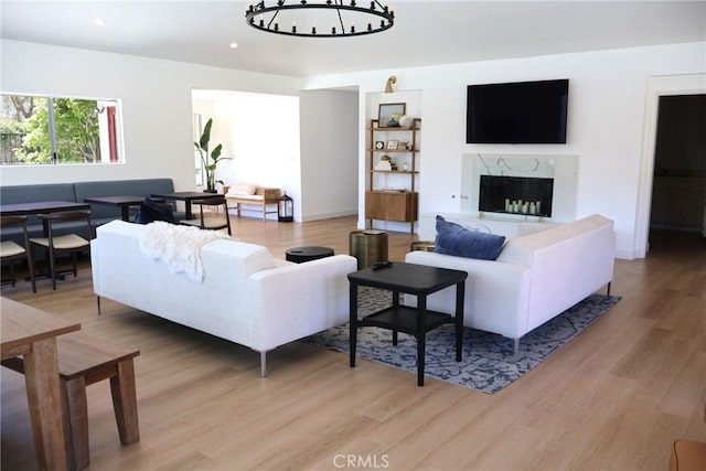 living room with light wood-style floors, a chandelier, a premium fireplace, recessed lighting, and baseboards