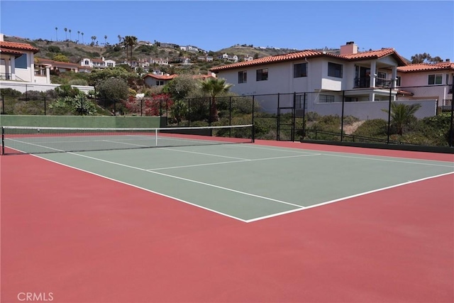 view of tennis court with community basketball court and fence