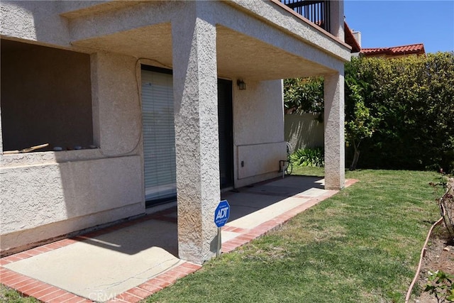 doorway to property featuring a lawn, stucco siding, and a patio