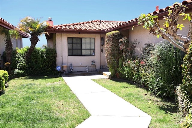 mediterranean / spanish home with a front lawn, stucco siding, and a tiled roof