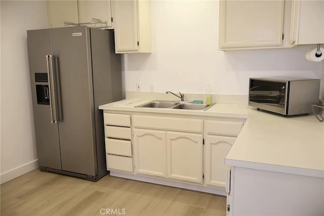 kitchen featuring appliances with stainless steel finishes, a sink, light wood-style floors, and light countertops