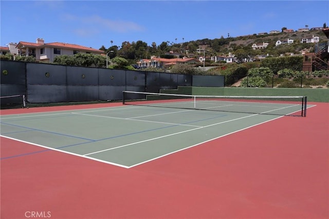 view of tennis court featuring community basketball court and fence