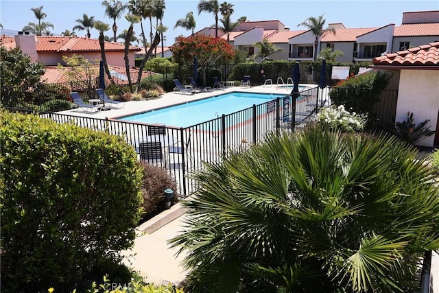 community pool with fence, a residential view, and a patio area