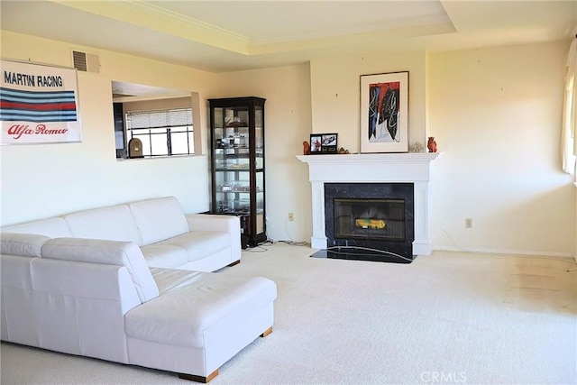 carpeted living area with a tray ceiling, a fireplace with flush hearth, crown molding, and baseboards