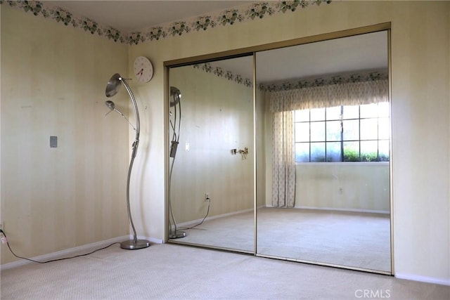 unfurnished bedroom with carpet flooring, a closet, and baseboards