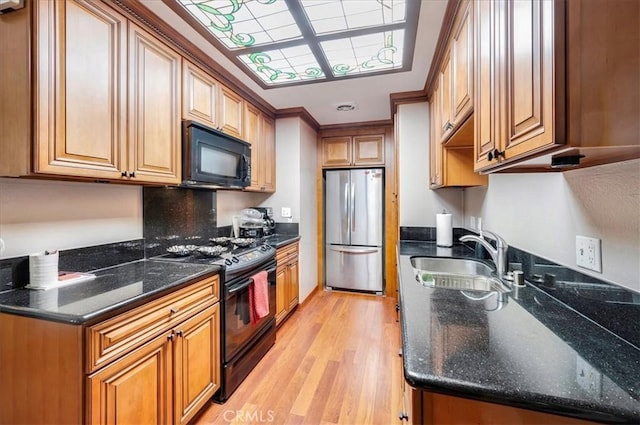 2049 Via Mariposa Unit E, Laguna Woods, CA 92637 - kitchen featuring black appliances, a sink, light wood-style floors, brown cabinets, and dark stone countertops