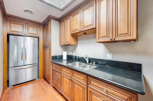 2049 Via Mariposa Unit E, Laguna Woods, CA 92637 - kitchen featuring freestanding refrigerator, a sink, light wood-style flooring, brown cabinets, and dark stone counters