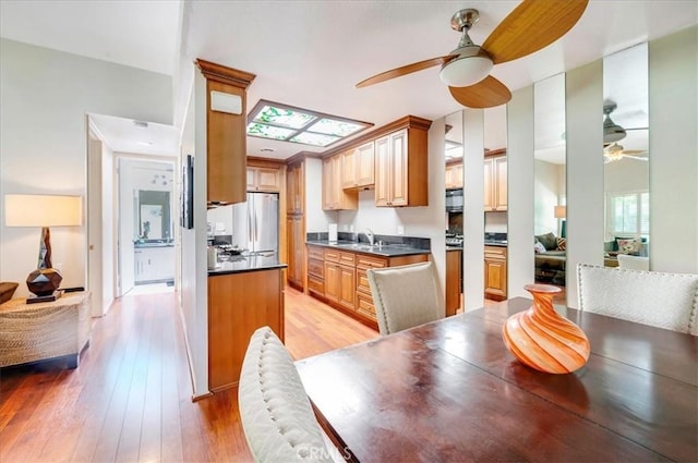 2049 Via Mariposa Unit E, Laguna Woods, CA 92637 - kitchen with ceiling fan, freestanding refrigerator, a sink, dark countertops, and light wood finished floors
