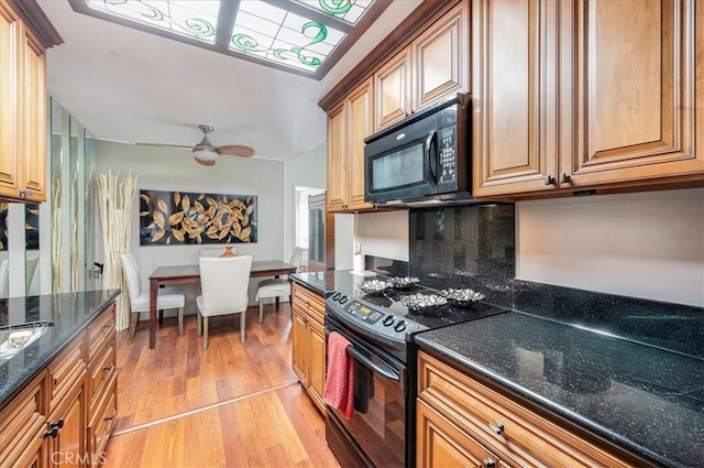 2049 Via Mariposa Unit E, Laguna Woods, CA 92637 - kitchen featuring black appliances, decorative backsplash, light wood finished floors, a ceiling fan, and dark stone countertops