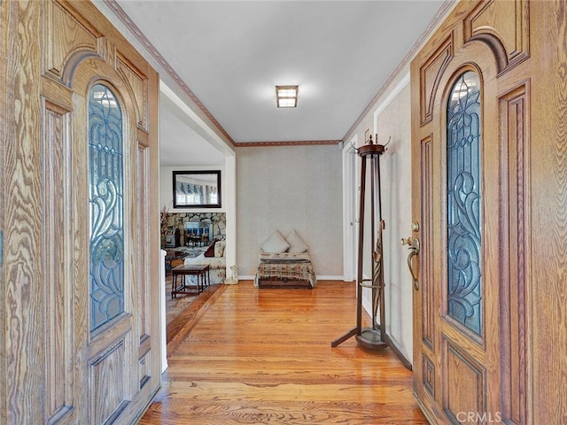 foyer entrance featuring light wood-style flooring, ornamental molding, and baseboards