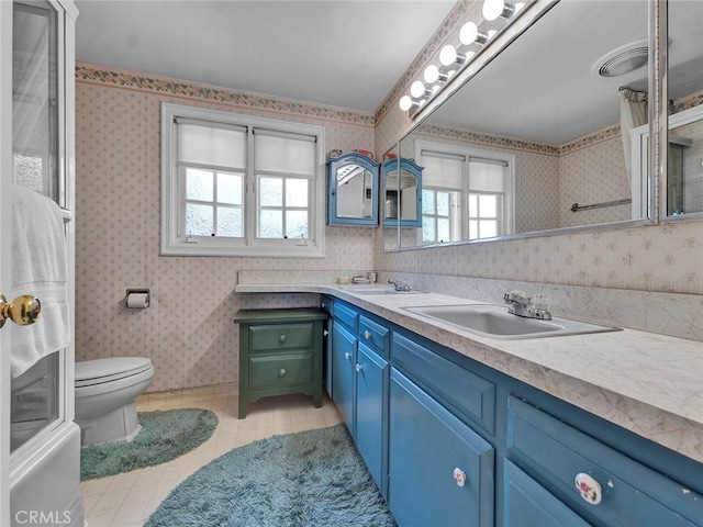 bathroom with tile patterned flooring, wallpapered walls, toilet, and double vanity