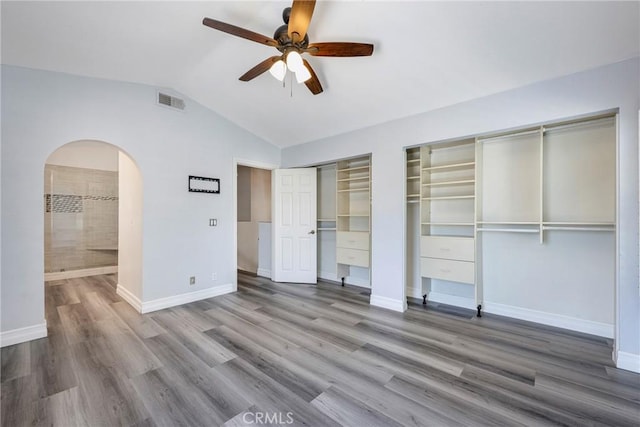 17275 Growers Cir, Yorba Linda, CA 92886 - unfurnished bedroom featuring two closets, vaulted ceiling, arched walkways, wood finished floors, and baseboards