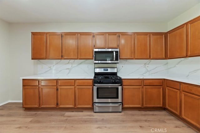 8167 Faircrest Rd, Riverside, CA 92508 - kitchen with appliances with stainless steel finishes, brown cabinets, decorative backsplash, light wood-style flooring, and light stone countertops