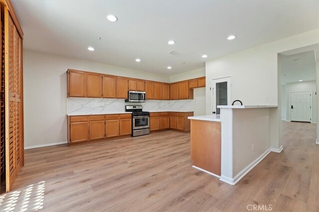 8167 Faircrest Rd, Riverside, CA 92508 - kitchen with stainless steel appliances, brown cabinets, light countertops, light wood-style floors, and decorative backsplash
