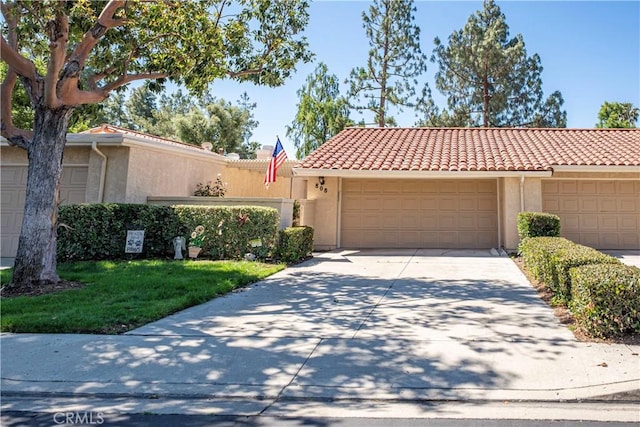 view of front of home featuring stucco siding, a tiled roof, concrete driveway, and a garage