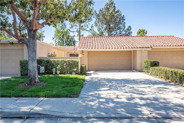 view of front of property with stucco siding, a tiled roof, concrete driveway, and an attached garage