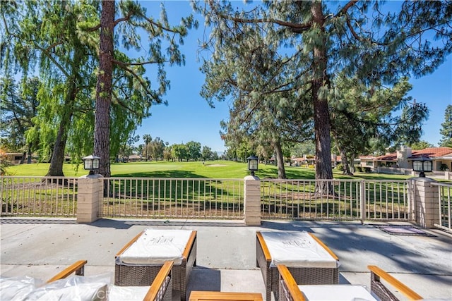 gate with golf course view and a patio