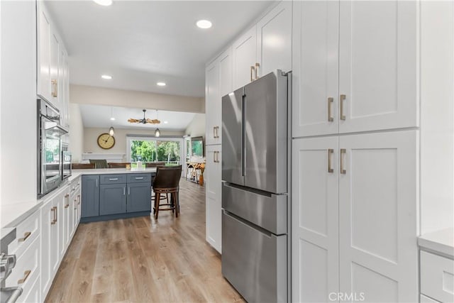 kitchen featuring appliances with stainless steel finishes, a peninsula, white cabinetry, light countertops, and recessed lighting