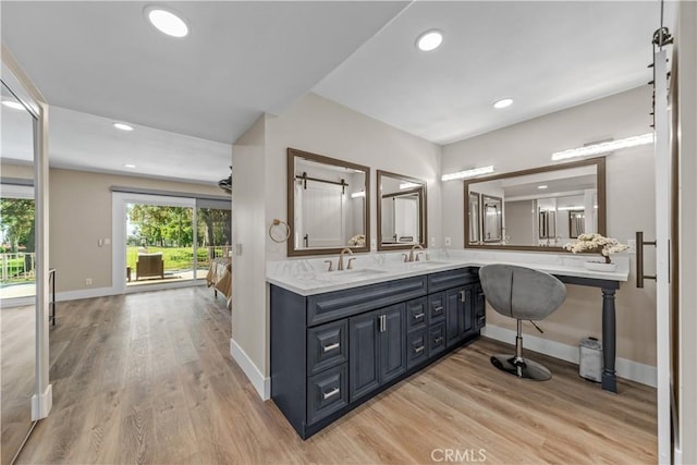 bathroom with wood finished floors, baseboards, recessed lighting, and double vanity