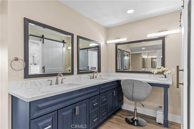 bathroom with wood finished floors, double vanity, and baseboards